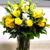 Yellow roses and lilies arranged in a clear glass vase