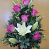 Pink roses and white lilies arranged in a red glass vase