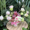 Pink and white floral arrangement in a white pot with a pink ribbon