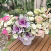 Pink and white roses with purple ornamental cabbage in a white vase