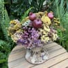 Dried flower arrangement with pomegranates in a low round container