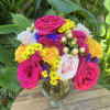 Mixed bouquet of pink, yellow, and white roses in a glass vase