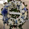 Large floral wreath with white and blue flowers and a ribbon banner