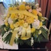 Yellow and white funeral spray with ribbon on a casket