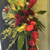 Tall tropical floral spray with red blooms and yellow orchids on a stand