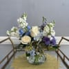 Mixed bouquet of white, blue, and purple flowers in a glass vase