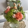 Bouquet of orange roses, green hydrangeas, and tulips in a glass vase