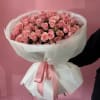 Large bouquet of pink roses wrapped in white paper with a pink ribbon