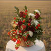 Basket arrangement of red roses and white flowers with strawberry accents and a large strawberry-print bow.