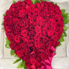 Heart-shaped bouquet of red roses with a pink ribbon