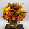 Autumn bouquet of yellow and peach flowers in a clear glass vase