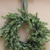 Green leafy wreath with a ribbon bow hanging on a wall