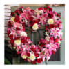 Heart-shaped floral wreath with pink lilies, red roses, and carnations