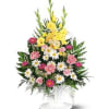 Standing floral arrangement with yellow, pink, and white flowers in a white pedestal vase