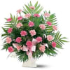 Pink carnations arranged in a white vase with a pink ribbon
