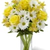 Yellow roses and white daisies in a clear glass vase