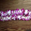 Two garlands of pink and white orchid blossoms on a wooden surface