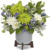 White and green floral arrangement in a ribbed vase on a stand