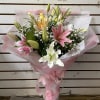 Bouquet of pink, white, and yellow lilies wrapped in pink paper