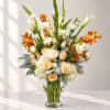 Tall bouquet of white and peach flowers in a clear glass vase