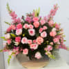 Large pink floral arrangement in a black container with roses and lilies