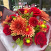 Bouquet of red roses and orange chrysanthemums wrapped in burgundy paper
