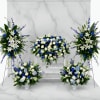 Blue and white floral funeral display with standing sprays and vase arrangements