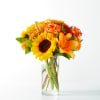 Bouquet of sunflowers, orange lilies, and roses in a clear glass vase