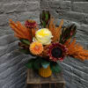Mixed floral arrangement in a yellow vase with orange accents