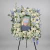 Large floral easel spray framing a portrait with white and blue flowers