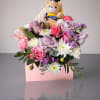 Pink and lavender roses with white mums in a pink box, topped with a teddy bear
