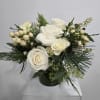 White rose arrangement in a dark vase with evergreen accents and cream berries