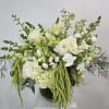 White floral arrangement with calla lilies, orchids, and trailing green accents in a vase