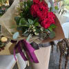 Bouquet of red roses wrapped in brown paper with a purple ribbon