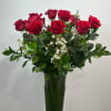 Red roses in a tall glass vase with white filler flowers