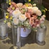 Blush and white floral centerpiece in a white vase with tall glass candle holders