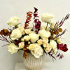 White and blush roses arranged in a textured vase with burgundy foliage