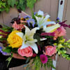 Mixed bouquet with white lilies, pink and yellow roses, and bright accent flowers
