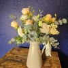 Peach and white flowers in a white vase with eucalyptus and a gold "love" pick