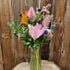 Pink lilies and mixed flowers arranged in a clear glass vase