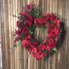 A 24&rdquo; open heart wreath lavished with red roses, spray roses, carnations