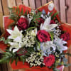 Bouquet of red roses and white lilies with mixed greenery in red wrap