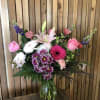 Mixed bouquet in a glass vase with pink roses, lilies, and purple blooms