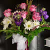Pink roses and white daisies in a red vase with a white bow
