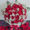 Red rose bouquet with baby's breath in a glass vase and ribbon