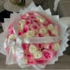 Pink and white rose bouquet wrapped in white paper with a satin bow