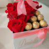 Red roses and gold chocolates in a pink ribboned gift box
