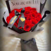 Bouquet of red roses wrapped in black and white paper with a love note