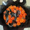 Orange rose bouquet wrapped in black paper with ribbon and spider decorations