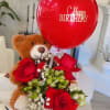 Teddy bear holding red roses with a birthday balloon